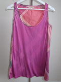 A sleeveless scoop-neck tank top in a vibrant magenta pink, featuring a geometric patchwork design with pink, beige, and gray panels along the sides and inner neckline, hanging on a white plastic hanger.